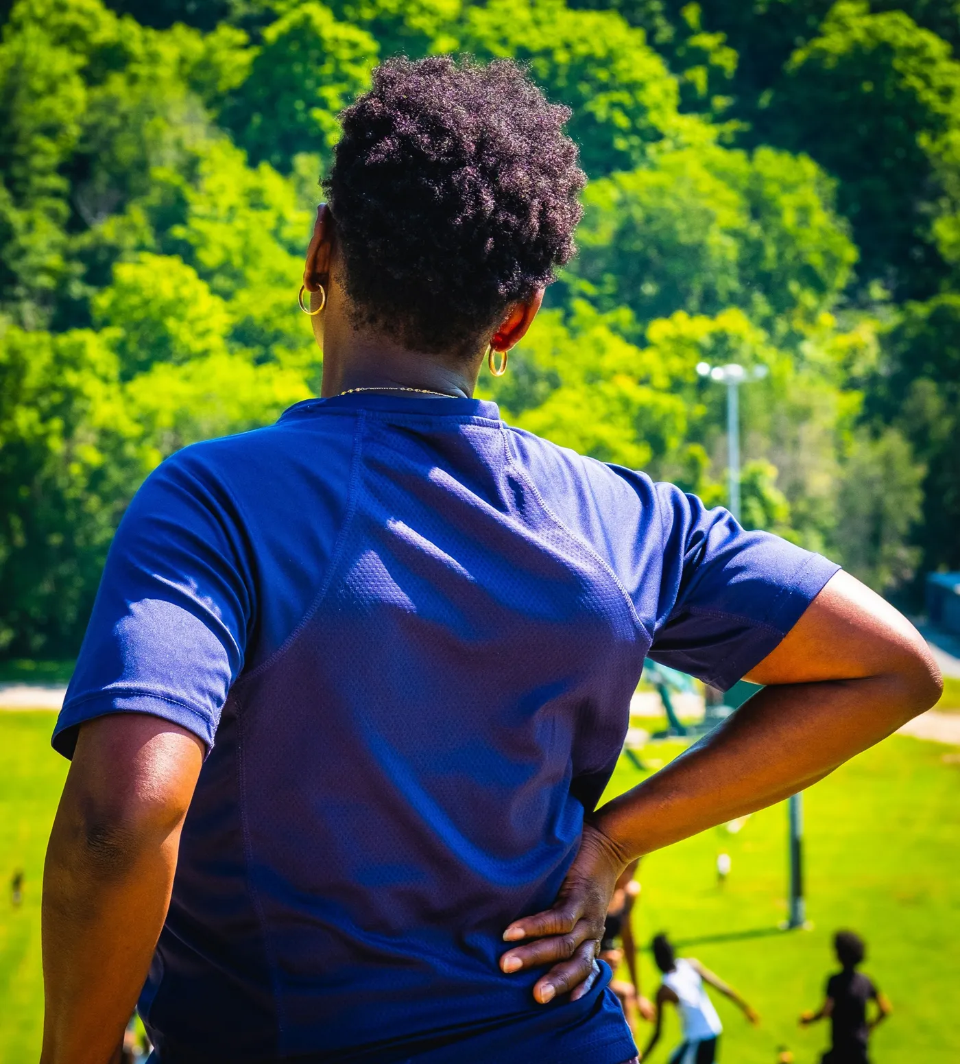A person standing outdoors with one hand resting on their lower back